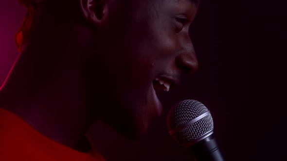 African Man Singing With Microphone Looking Aside In Studio Cropped
