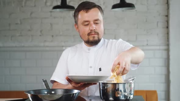 Chef is Cooking Italian Pasta He Puts Raw Macaroni From Plate to Pan Bowl