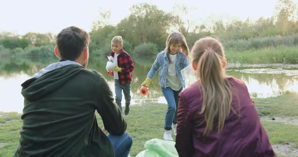 Parents Watching How Their Children Collecting Rubbish and Putting Into Plastic Bags