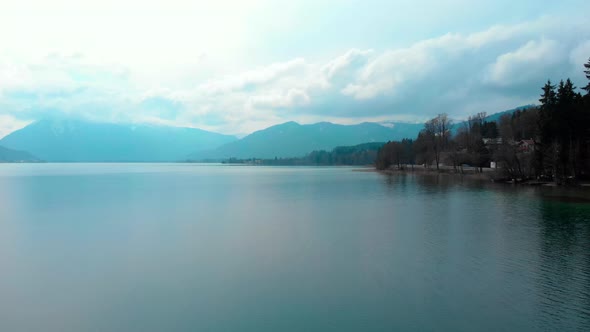 Flying along the coastline of the Tegernsee on a cloudy spring day.