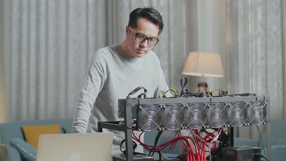 Asian Man Wearing Glasses Looking At The Cryptocurrency Mining While Working With A Laptop