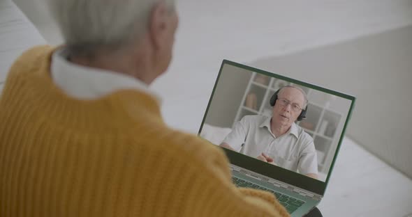 Aged Man Is Conducting Online Webinar and Retired Person Is Watching Him on Screen of His Laptop