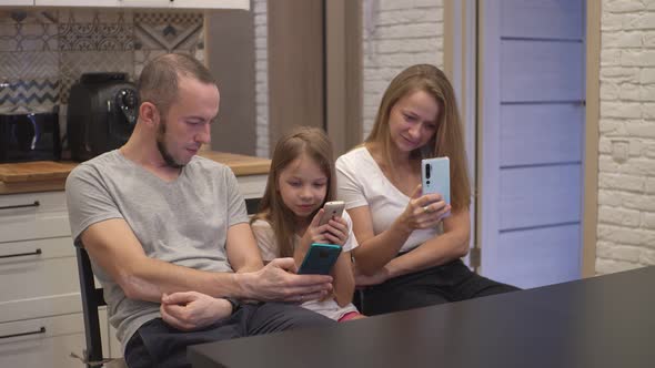 Mom Dad and Daughter Look at Smartphones