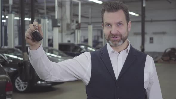 Portrait of Confident Successful Caucasian Man Holding Car Keys in Right Hand and Looking at Camera