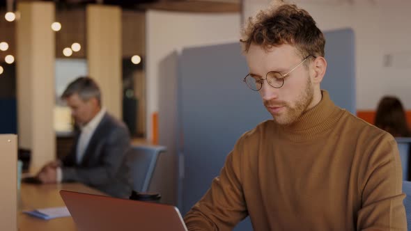 Waist Up Portrait View of the Caucasian Man Typing at the Laptop Keyboard While Working with