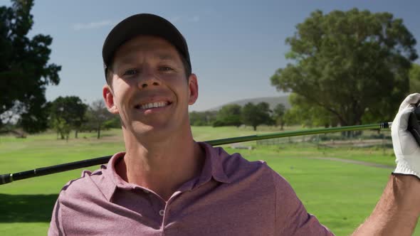 Caucasian male golfer smiling at camera on a golf course