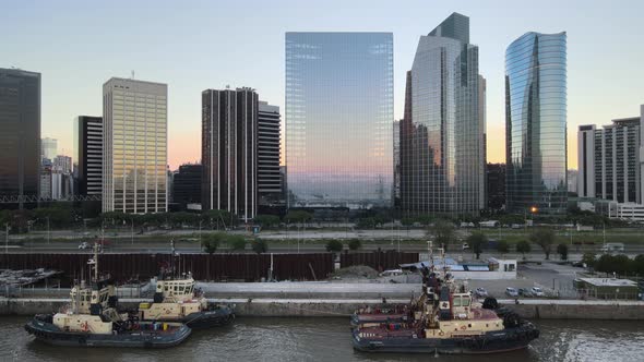 Aerial of boats in Puerto Madero docks near Paseo del Bajo highway and skyscrapers at sunset, Buenos