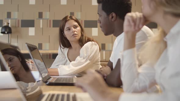 Startup Team Sitting at Table with Laptops