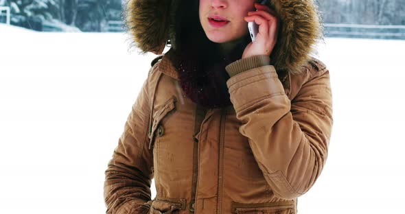 Smiling woman in fur jacket talking on mobile phone