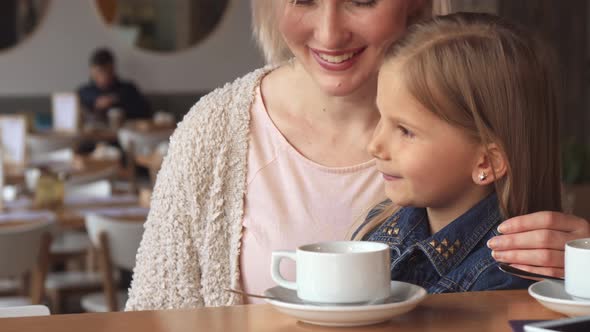 Woman Shows Her Daughter Something at the Cafe