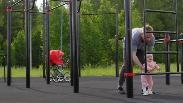 Caucasian Dad Walking with Baby Daughter at Outdoor Gym