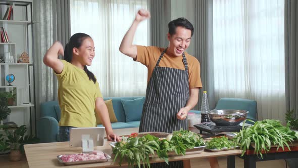 Asian Man Father Giving High Five To Happy Little Child Daughter While Cooking At Home
