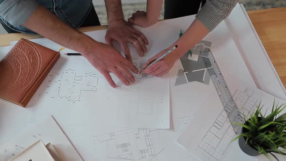 Close Up Hands of Two Workers Discussing Building Drawings in Office. Closeup Shooting of Arms