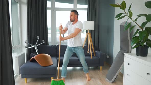 Man Cleaning the House and Having Fun Dancing and Singing with a Broom