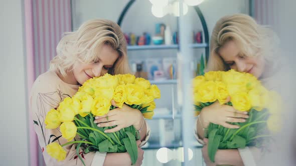 The Girl Enjoys Aroma of a Bouquet of Yellow Tulips