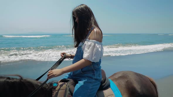 Cute Chinese Teenager Rides a Horse On The Beach In Bali