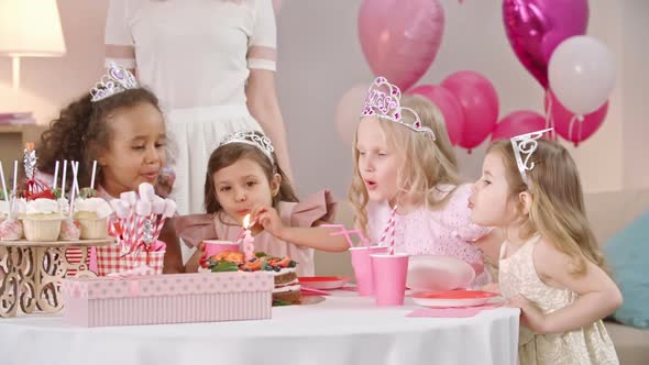 Little Girls Blowing Out Candle on Birthday Cake