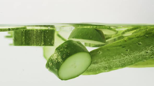 Cucumber Slices Dropped And Float Into The Water On White Background. - studio shot