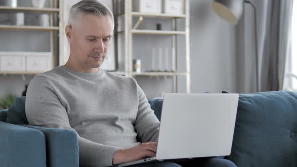 Casual Gray Hair Man Working with Laptop in His Lap