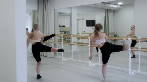 Three young girls dance in a white bright studio in front of a mirror. Slow motion, smooth motion.