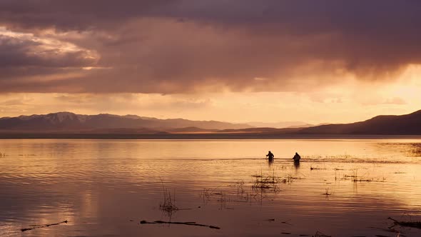 Fishermen standing in Utah Lake during colorful sunset