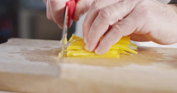 Slow motion close up of a chef knife slicing a yellow bell pepper