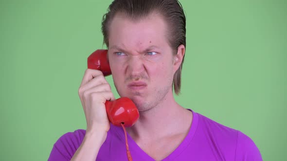 Face of Angry Young Man Using Old Telephone and Walking Away