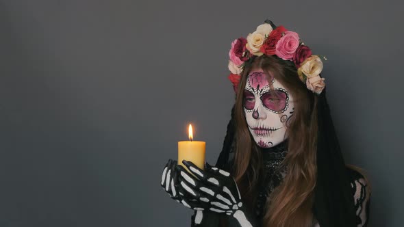 Woman in the Image of Death Santa Muerte or Sugar Mexican Skull with a Burning Candle in Her Hands