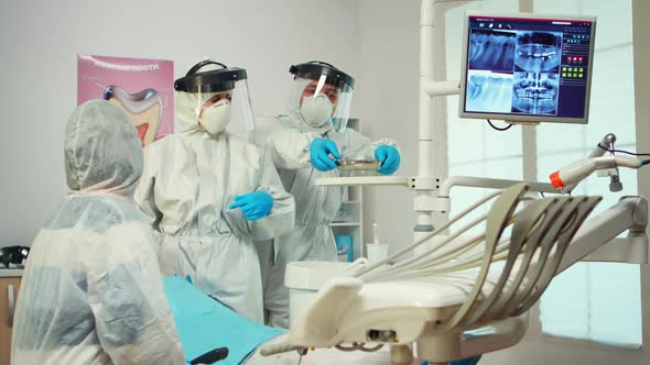 Dentist in Ppe Suit Standing Near Girl Patient Talking with Mother