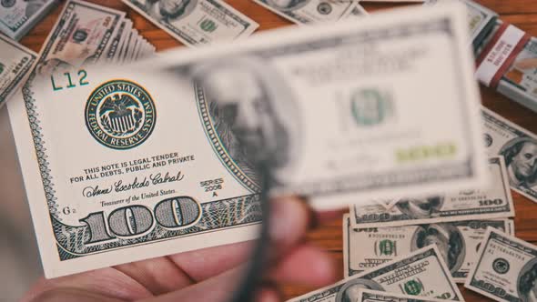 One Hundred Dollars Inspecting Under Magnifying Glass on Money Background