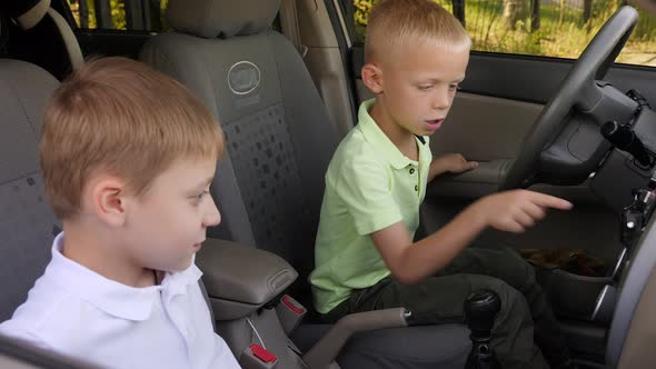 Curious Kids are Sitting Behind the Wheel in Dad's Car and Pushing Buttons