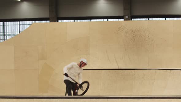 Young Man Riding on the Plywood Ramps on His Sports Bike and Performing Tricks