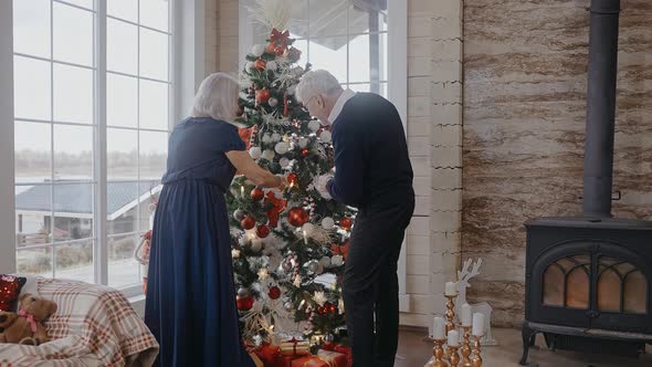 Grandparents Decorating Christmas Tree Talking Smiling and Hugging