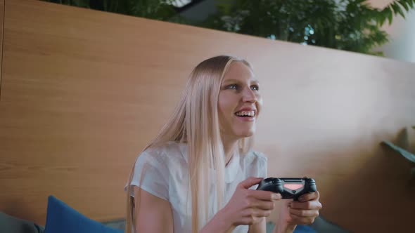 Woman Gaming and Relaxing in Modern Office. Young Formal Woman in Skirt Chilling on Sofa in