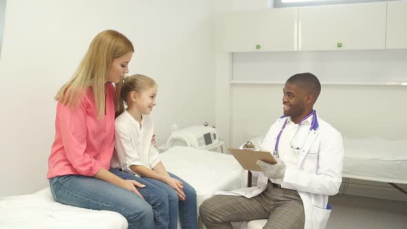 Young Doctor Pediatrician Talking with Child Girl Patient