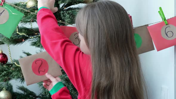 Close Up Portrait of Adorable Little Girl Taking Second Envelope of Advent Christmas Calendar