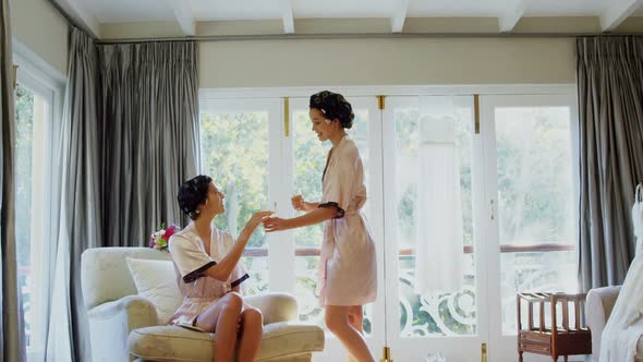 Excited bridesmaids in nightdress and hair rollers tossing a glass of champagne 4K 4k