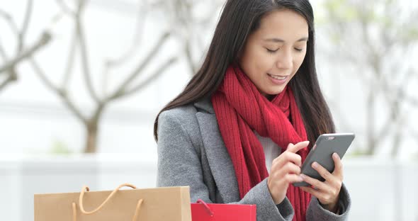 Shopping woman holding paper bag and use of mobile phone in city