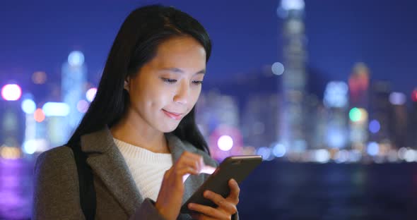 Business woman using cellphone in Hong Kong city at night