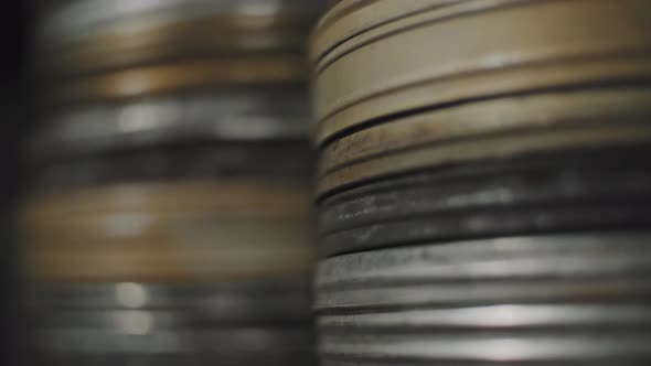 Close movement of the camera to old round metal boxes with film strip in them. Selective focus.