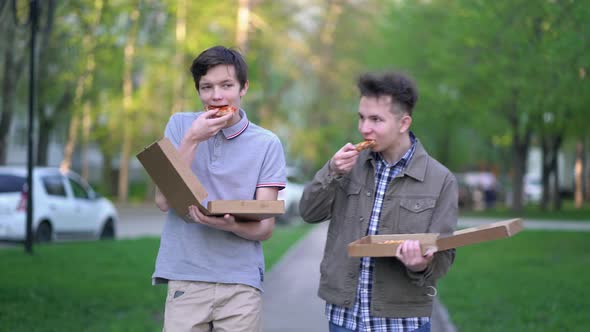 Two Friends are Eating Pizza Outdoors