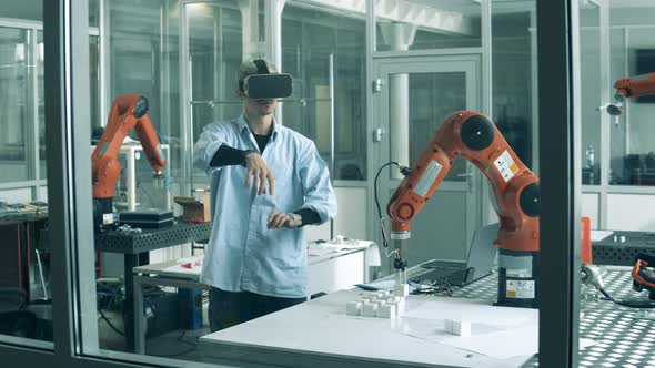 Male Researcher Wearing VRglasses in a Laboratory with a Robot