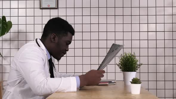 Afro American Male Doctor Looking at X-ray of a Brain