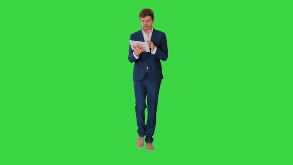Smiling Businessman Using Digital Tablet While Walking on a Green Screen, Chroma Key.