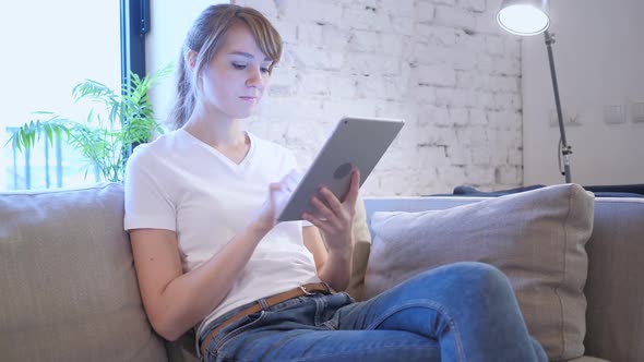 Woman Browsing Internet on Tablet PC Sitting on Couch