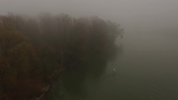 Alone Man is Floating on a Board on a River in a Very Thick Fog