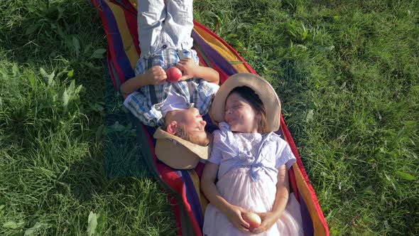 Cheerful Children in Straw Hats Are Lying on Blanket with Apples in Their Hands and Communicate at