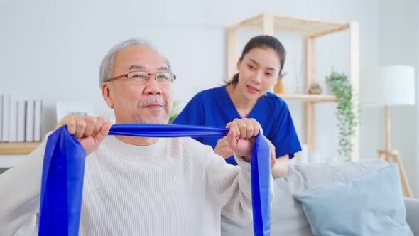 Asian senior older man doing physical therapy with support from nurse.