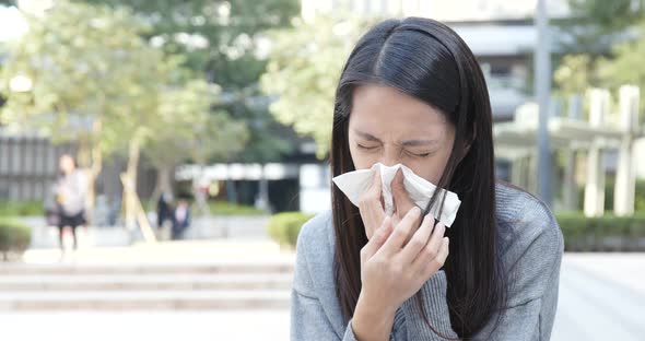 Woman sneezing at outdoor