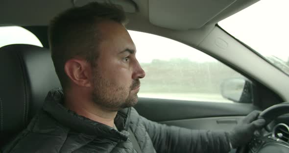 Young Man is Driving a Car on a Rainy Day